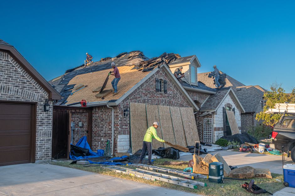 Residential roof during professional inspection showing various roofing materials and structural features