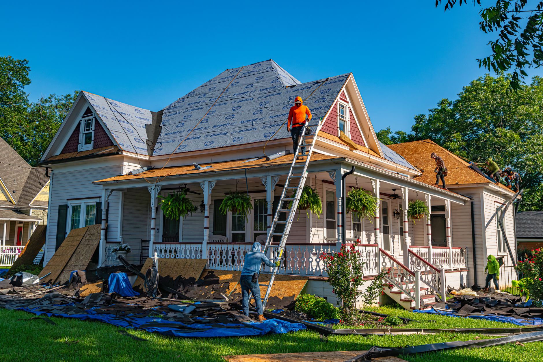 Roofing contractor in safety gear working on residential roof repair